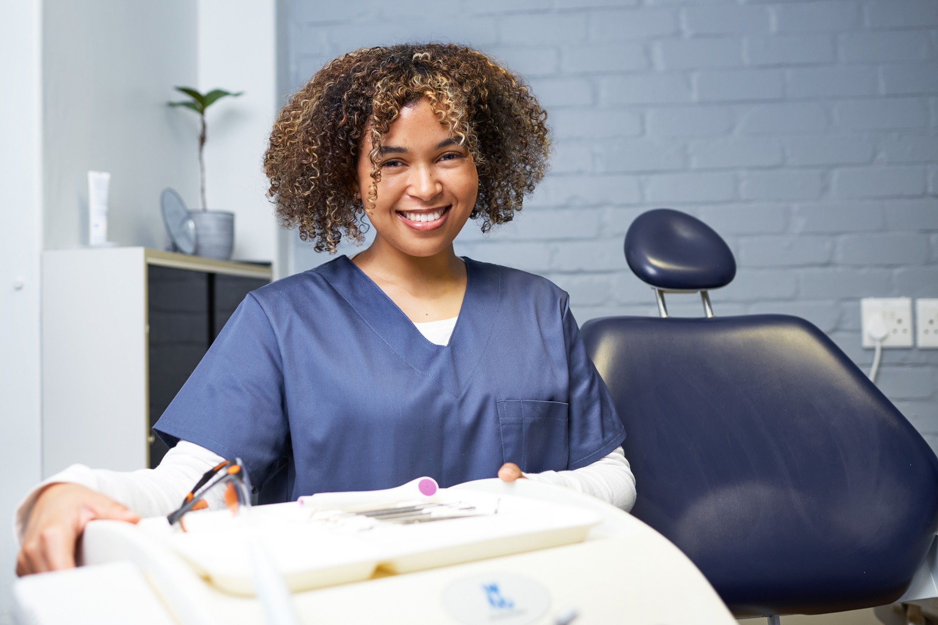 Smiling Female Dental Professional in a Modern Dental Office Setting with Equipment